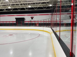 Empty indoor ice hockey rink with red seats.